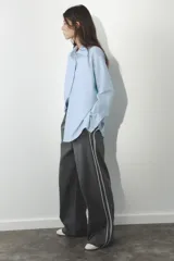 Pantalón de tiro alto negro a rayas verticales blancas, con cintura elástica ajustable con cordones, bolsillos delanteros y banda lateral blanca.