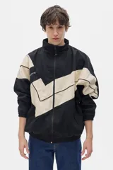 Campera estilo olímpica con cierre frontal, corte oversized y elástico en la cintura. Diseño con bloques de color negro y beige.