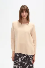 Sweater liso color beige, de corte holgado, con cuello a la base y broches decorativos en los laterales.