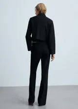 Pantalón de vestir negro acampanado, de tiro alto, con trabillas, bolsillos laterales y cierre oculto de botón, gancho y cremallera.