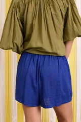 Camisa verde militar de algodón con mangas murciélago, corte holgado y botones florales azules.