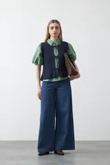 Chaleco tejido de punto color beige con trama texturada y diseño liviano. Presenta cuello a la base, silueta recta y cierre frontal mediante tres lazos delicados.