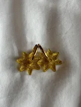 Par de aros dorados con forma de estrella negra.