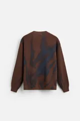 Sweater marrón de punto con cuello redondo y manga larga. Tiene un estampado irregular con efecto spray en color azul.