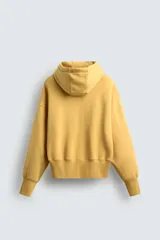 Sudadera con capucha color ocre, de corte holgado y mangas largas. Estampado frontal con texto en azul.