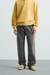 Pantalón gris de corte relaxed fit, con cinco bolsillos, efecto lavado, aplicación de tira y bolsillo multifunción en perneras. Cierre frontal con cremallera y botón.