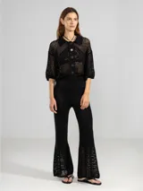 Camisa corta de punto abierto color negro, con cuello polo, mangas 3/4 y cierre frontal con botones.