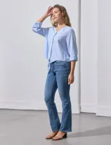 Blusa de algodón a rayas verticales finas en tonos blanco y lila, con escote en V, abertura frontal con botones y mangas largas regulables con presilla y botón. El ruedo termina anudado al frente.