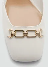 Zapato blanco de cuero sintético con tacón bloque, punta cuadrada, cierre con hebilla y detalle de eslabones dorados.