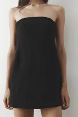 Vestido corto negro sin mangas, con escote palabra de honor y pespuntes marcados. Cierre trasero con cremallera oculta.