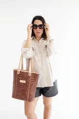 Bolso tipo tote de cuero marrón con textura de cocodrilo, doble asa corta y cierre superior.