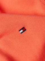 Chomba Tommy Hilfiger 1985 color naranja, de corte regular, con cuello tipo chomba, cartera de dos botones y logo bordado en el pecho.