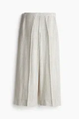 Pantalón ancho de tiro alto con elástico en la parte posterior de la cintura y cierre oculto con corchete en un lado. Bolsillos laterales discretos y piernas amplias con pliegues adelante y atrás. Diseño a rayas verticales grises y blancas.