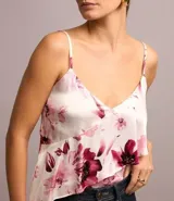 Blusa de viscosa satinada con estampado floral, breteles finos ajustables, escote en pico y volado diagonal.