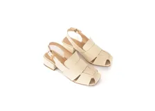 Sandalia de cuero trenzado color hueso, con punta cuadrada, talón abierto, pulsera ajustable con hebilla metálica y taco ancho forrado en cuero.