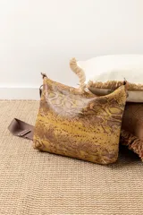 Cartera dorada con textura de piel de serpiente, cierre superior con cremallera y correa de hombro desmontable.