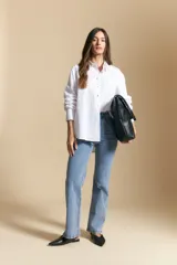 Jean de corte recto y tiro medio, color gris oscuro con efecto lavado. Presenta apliques de tachas metálicas pequeñas en la zona de los bolsillos delanteros.