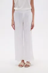Pantalón blanco de algodón con calce recto y tiro bajo. La tela presenta bordados tipo calado (broderie) a lo largo de toda la prenda.