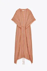 Vestido largo tipo kaftán confeccionado en lino a rayas verticales en tonos naranja y verde. Tiene cuello redondo con escote en V, mangas cortas amplias, acabado deshilachado y cinturón de cordón en el mismo tejido.