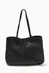 Cartera tote negra de cuero sintético con doble asa de hombro y dije metálico circular con el nombre de la marca.