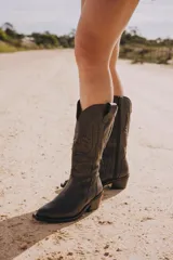 Bota texana de caña alta color beige, confeccionada en cuero vacuno con cierre interno YKK. Presenta bordados decorativos en la caña y taco de madera con folia de cuero.