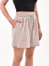 Short celeste de tejido arrugado con cintura elastizada y lazo de ajuste.