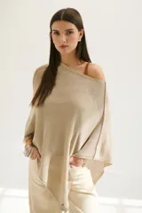 Poncho color beige de tejido de punto con cuello asimétrico.