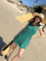 Vestido corto tejido a crochet color marrón con rayas horizontales blancas y cuello y sisas con borde rojo.