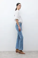 Jean de mezclilla azul medio, corte oxford o bota ancha, tiro medio/alto, con costura central marcada en el frente de ambas piernas.