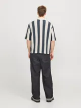 Polo de hombre con tejido texturizado a rayas verticales color crema y gris, corte holgado, cuello tipo polo, mangas cortas y cierre con botones.