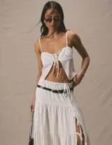 Pollera larga blanca de tiro alto, con volados en capas y abertura lateral ajustable con cordones.