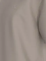 Remera color beige de algodón regenerativo con cuello redondo, mangas cortas y logo CK bordado en el pecho. Presenta un diseño de paisaje gráfico en el frente.