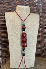 Collar largo con cordón de gamuza color borgoña y cuentas de piedra de diferentes colores: verde, negro y rojo.