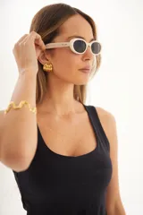 Lentes de sol con marco ovalado color crema y lentes oscuros, con protección UV400.