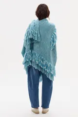 Ruana tejida en lana merino color celeste con flecos.