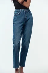 Jeans de tiro alto color celeste, corte mom fit, con cinco bolsillos y cierre frontal con cremallera y botón.