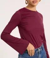 Blusa manga larga godê color borgoña, confeccionada en microfibra con fruncido en los hombros y laterales.