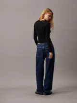 Remera negra de punto modal elástico, con cuello redondo, mangas largas y detalle plisado en un lateral.