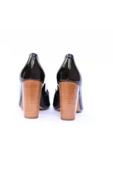 Zapato de tacón alto color negro charol, con punta fina y tacón geométrico con textura de madera.