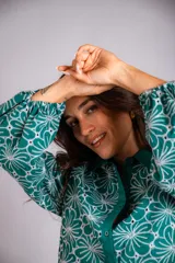 Camisa celeste con estampado de flores blancas, corte clásico, cuello camisero y mangas largas abullonadas.
