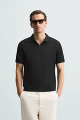 Polo azul marino de punto con textura acanalada vertical, corte regular fit, cuello solapa con abertura frontal y mangas cortas.