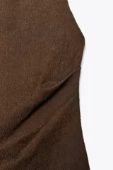 Top marrón de cuello halter con textura y drapeado lateral. Espalda y bajo asimétricos. Cierre en cuello con botones.