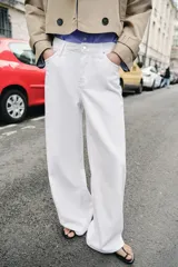 Jeans blancos de tiro medio con cinco bolsillos y pernera ancha. Cierre frontal con botones.