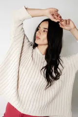 Poncho tejido de punto color crudo con lurex, de calce suelto y relajado.