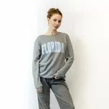 Sweater gris de corte clásico con cuello redondo y puños y cintura acanalados. Estampado frontal con la palabra "Florida" en letras celestes con borde blanco.