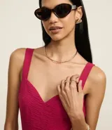Vestido midi evasê sin mangas color fucsia, confeccionado en tejido airflow con textura arrugada. Presenta escote corazón, breteles medianos con elásticos, recortes fruncidos en la cintura y en el bajo, y cierre lateral con cremallera invisible.