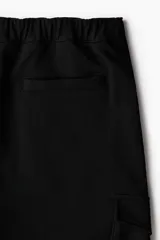 Pantalón jogger negro de felpa pesada de mezcla de algodón, corte slim fit, con cintura elástica ajustable con cordón, cierre decorativo, bolsillos al bies, bolsillo trasero y bolsillos cargo con solapa y botones a presión ocultos en las piernas.