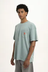 Remera color celeste con bolsillo en el pecho y logo estampado en color naranja.