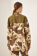 Chaqueta de camuflaje con estampado de flores en tonos marrones y verdes, con cierre frontal y bolsillos.