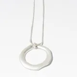 Collar plateado con dije circular irregular.